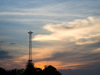 Silhouette spotlight pole like UFO with sunset and cloudy background