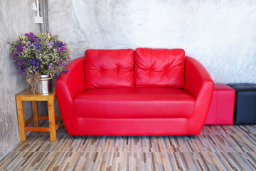 Red sofa in a room with wood tiled floors.
