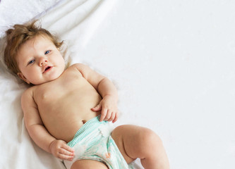 Funny beautiful little baby lying on a white diaper.