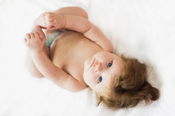Funny beautiful little baby lying on a white diaper.
