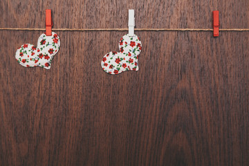 Fototapeta na wymiar two hearts hanging from a rope on a wooden background