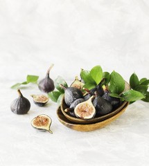 dark blue Fresh figs in a wooden bowl on a white marble table, selective focus
