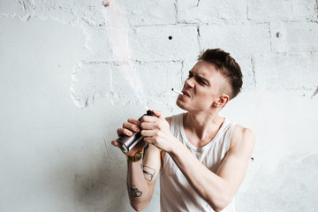 Handsome man standing on floor with gas spray and cigarette