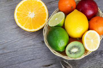 Fototapeta na wymiar Citrus fruit in a basket on a gray wooden background