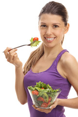 Joyful young woman eating a salad