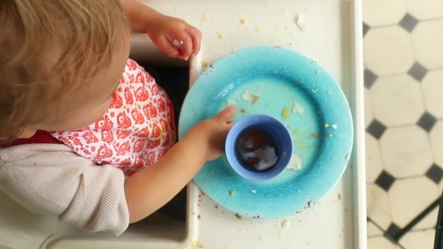 Baby playing with food. Happy toddler blonde baby boy having fun with food leftovers