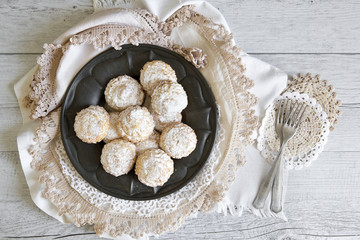 Coconut biscuits with icing sugar over pewter plate