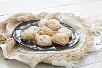 Coconut biscuits with icing sugar over pewter plate