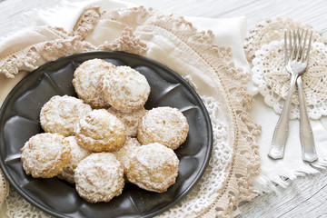 Coconut biscuits with icing sugar over pewter plate