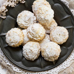 Coconut biscuits with icing sugar over pewter plate