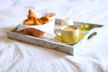 Breakfast in bed. Gray wooden tray with croissants and tea.