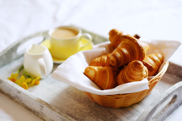 Breakfast in bed. Gray wooden tray with croissants and tea.