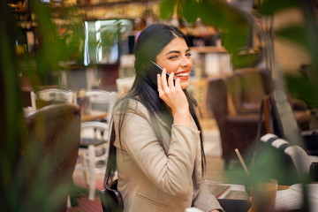 Woman using talking on cell phone at cafe