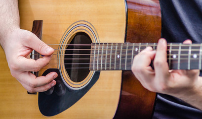 Musician's hands plays a chord on a yellow acoustic guitar