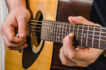 Fototapeta na wymiar Skilled hands play yellow acoustic guitar