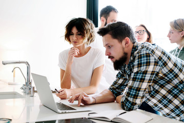Group of igital designers are working on a new concept. Young hipsters are discussing new start up project. Colleagues are consolidating the information while working on the annual marketing report.
