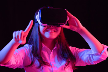 Asian Chinese young woman using virtual reality smart glasses play game.low key photo