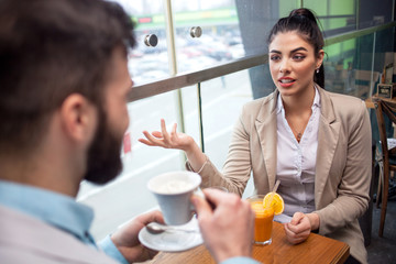 Two casual business travellers having a conversation at an airport café
