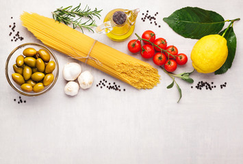 Frame with spaghetti and various ingredients for cooking pasta on a white background, top view. Flat lay