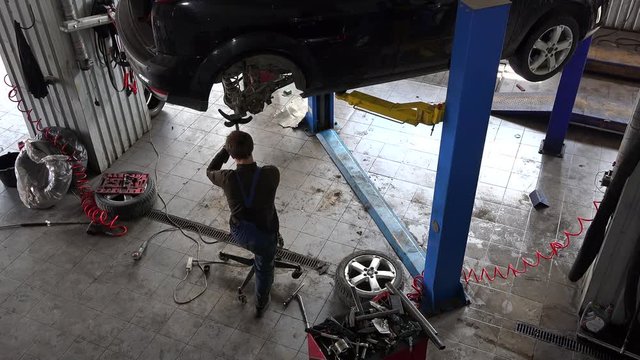 male mechanic repair lifted up automobile in car repair shop