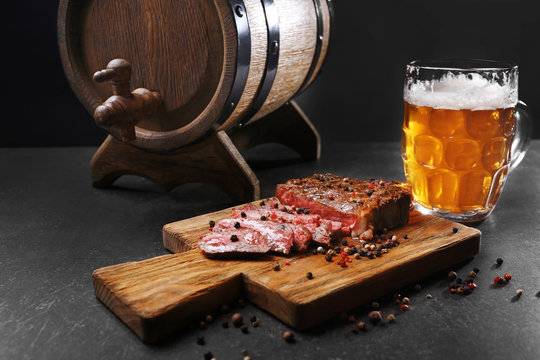 Tasty grilled steak with beer on cutting board