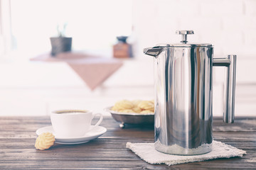 New coffee maker and cup of fresh drink with cookies on kitchen table