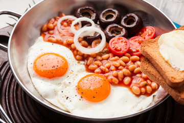Full English Breakfast with fried eggs, beans, toasts, tomatoes , mushrooms