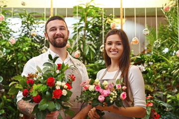 Male and female florists with beautiful bouquets in greenhouse