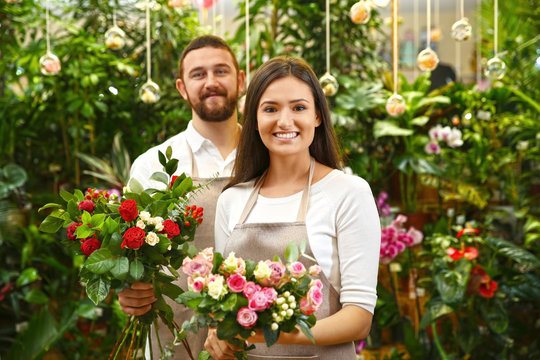 Male and female florists with beautiful bouquets in greenhouse