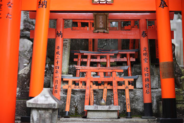Fototapeta na wymiar Red wooden sacrificial gate Torii with the names of donors on the territory of a Shinto temple