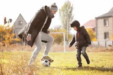 Foto op Plexiglas Father and son playing football on soccer pitch © Africa Studio