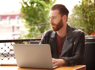 Handsome young man with laptop at cafe