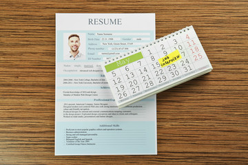 Fototapeta na wymiar Calendar with job interview reminder and resume on wooden table
