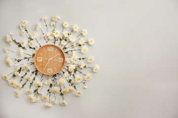 Clock decorated with flowers on light wall