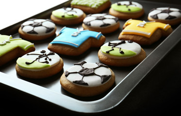 Football cookies on baking tray, closeup