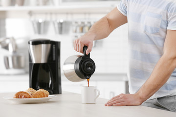 Handsome young man drinking coffee at home