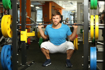 Young handsome man with barbell training in gym