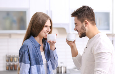 Cute young couple drinking coffee in kitchen