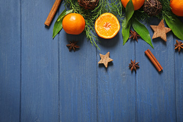 Composition of tangerine, spices and coniferous branches on wooden background