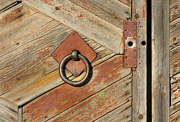 Wooden old fence with an iron grip. Metal circle on a rustic door. Retro and vintage.