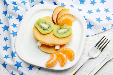 Plate with creative homemade pancakes on wooden table