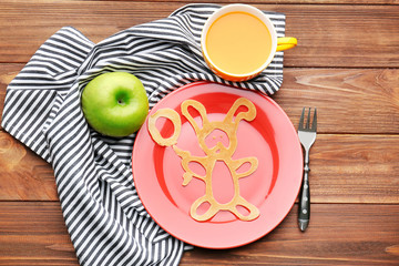 Plate with creative homemade pancake on wooden table
