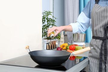 Woman pouring oil in pan at kitchen