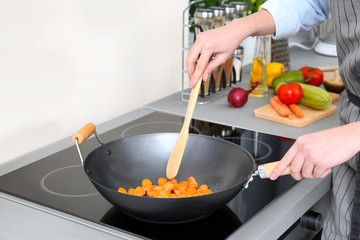 Woman mixing vegetables in pan at kitchen