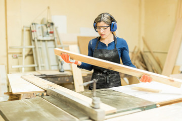 Female carpenter inspecting a piece of wood