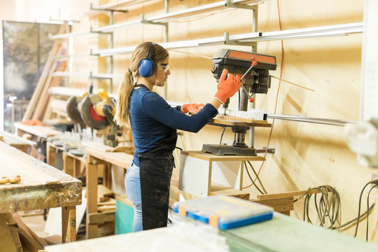 Female carpenter using a drill press