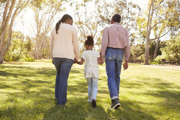 Grandparents And Granddaughter Walking In Park Together