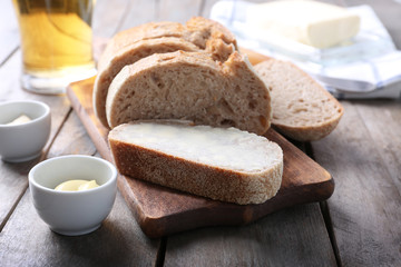 Wooden cutting board with sliced loaf of beer bread and butter on table