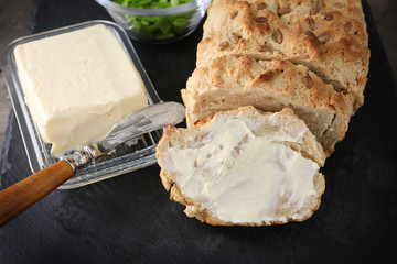 Sliced loaf of beer bread with butter on slate plate