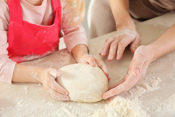 Young mother with daughter making biscuits on table